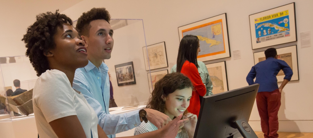 students in an art gallery looking at a computer monitor