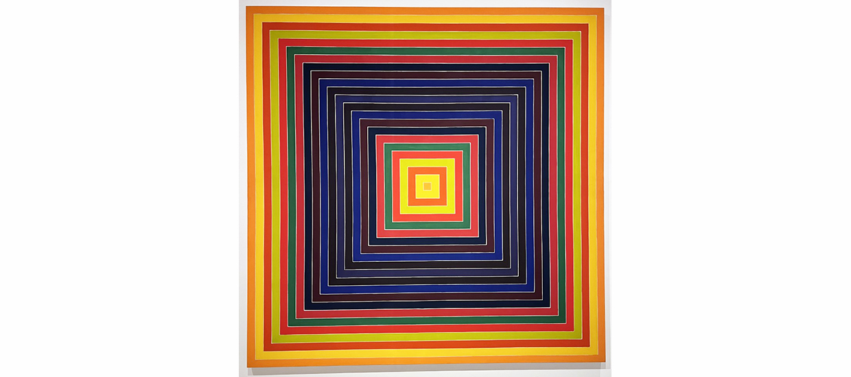 This 11 foot by 11 foot square acrylic painting features a series of concentric squares in oranges, reds, greens, and blues, with a small orange square at its center. The square bands of color resemble thin frames nestled one inside the other, receding toward the small orange square at the center. The precisely aligned corners of the squares, the arrangement of colors (warm colors at the edges, dark near the middle, and bright at the center), and the small square at the core, combine to create  a tunnel effect or illusion. 